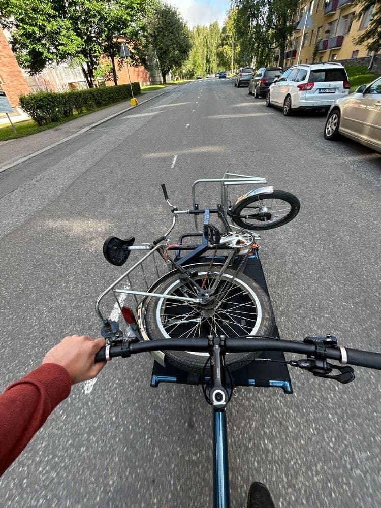 Pyöräilijän näkymä kadulta, jonka varrella on pysäköityjä autoja ja vastaan tulee toinen pyöräilijä