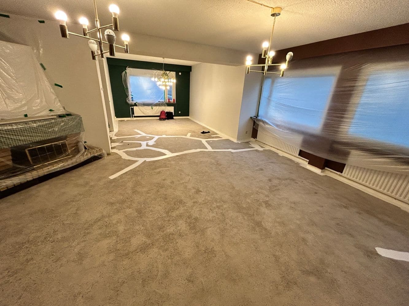 Remontissa oleva huone, jonka betonilattiaan on piirretty liitumerkintöjä